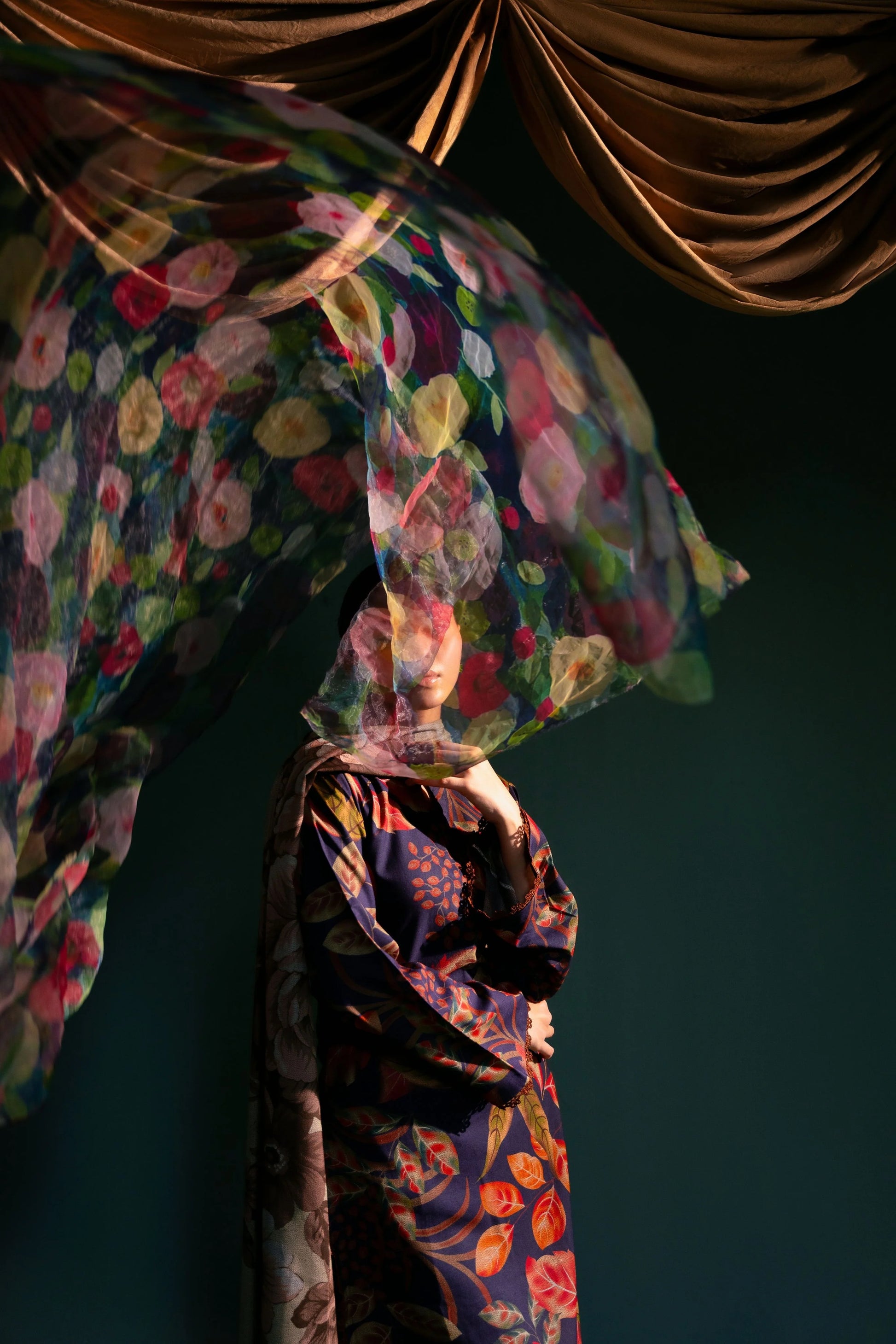 Foulard léger en mouvement, révélant son imprimé floral coloré sur fond sombre.