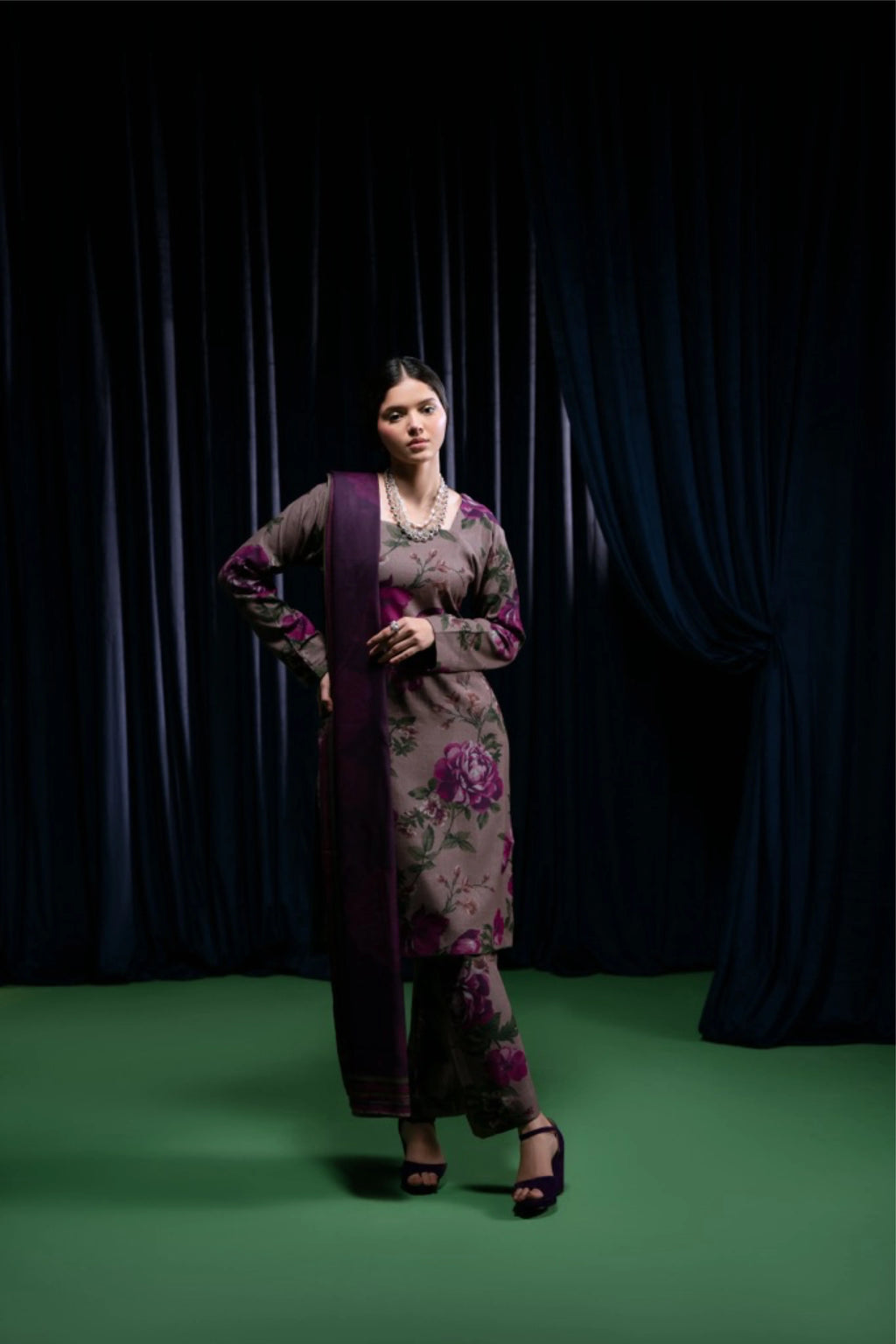 femme en shalwar kameez prune à imprimé floral devant un rideau sombre