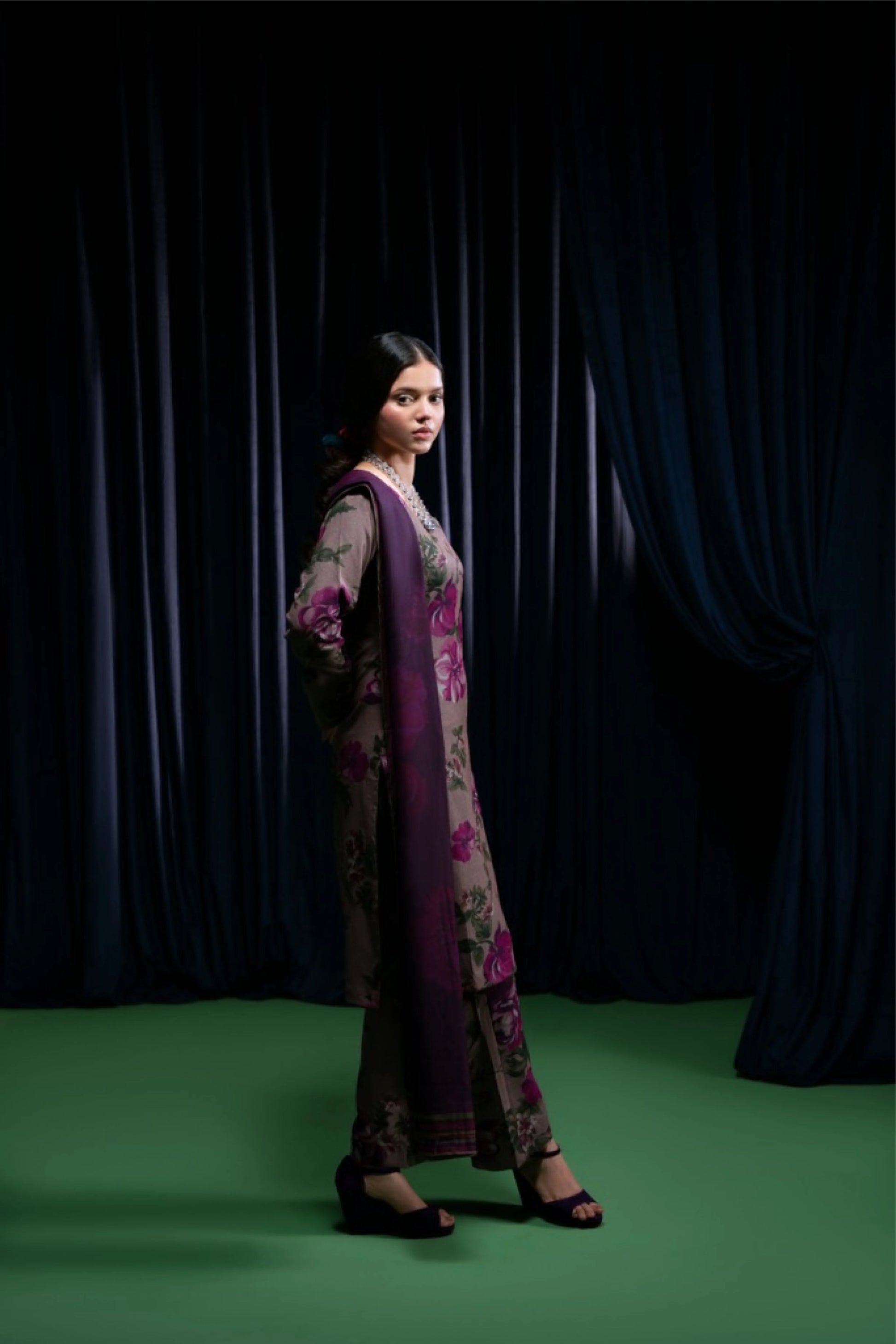 profil du modèle portant un shalwar kameez prune fleuri, fond rideau foncé