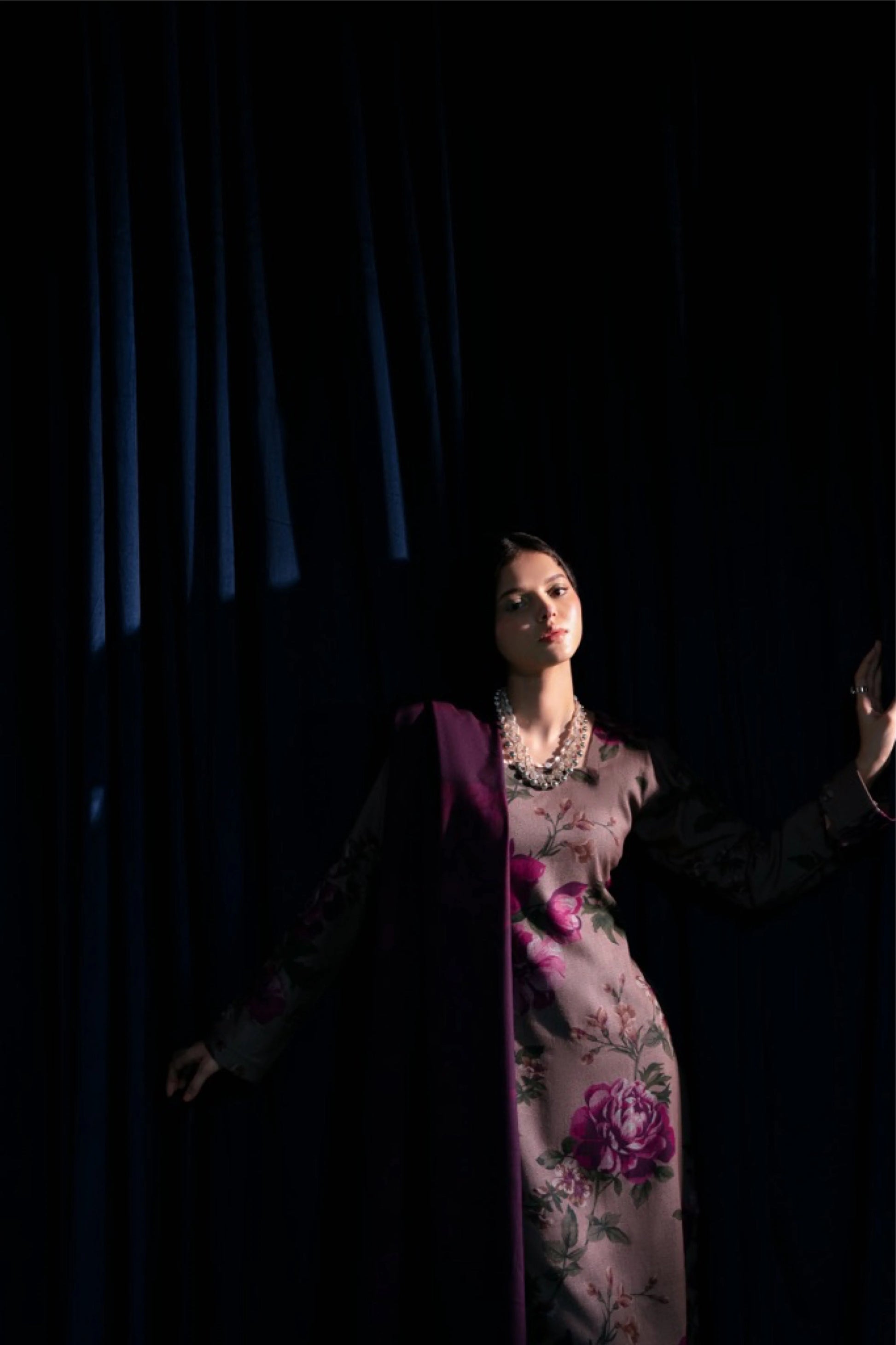 modèle posant dans l'ombre avec robe prune fleurie, ambiance dramatique