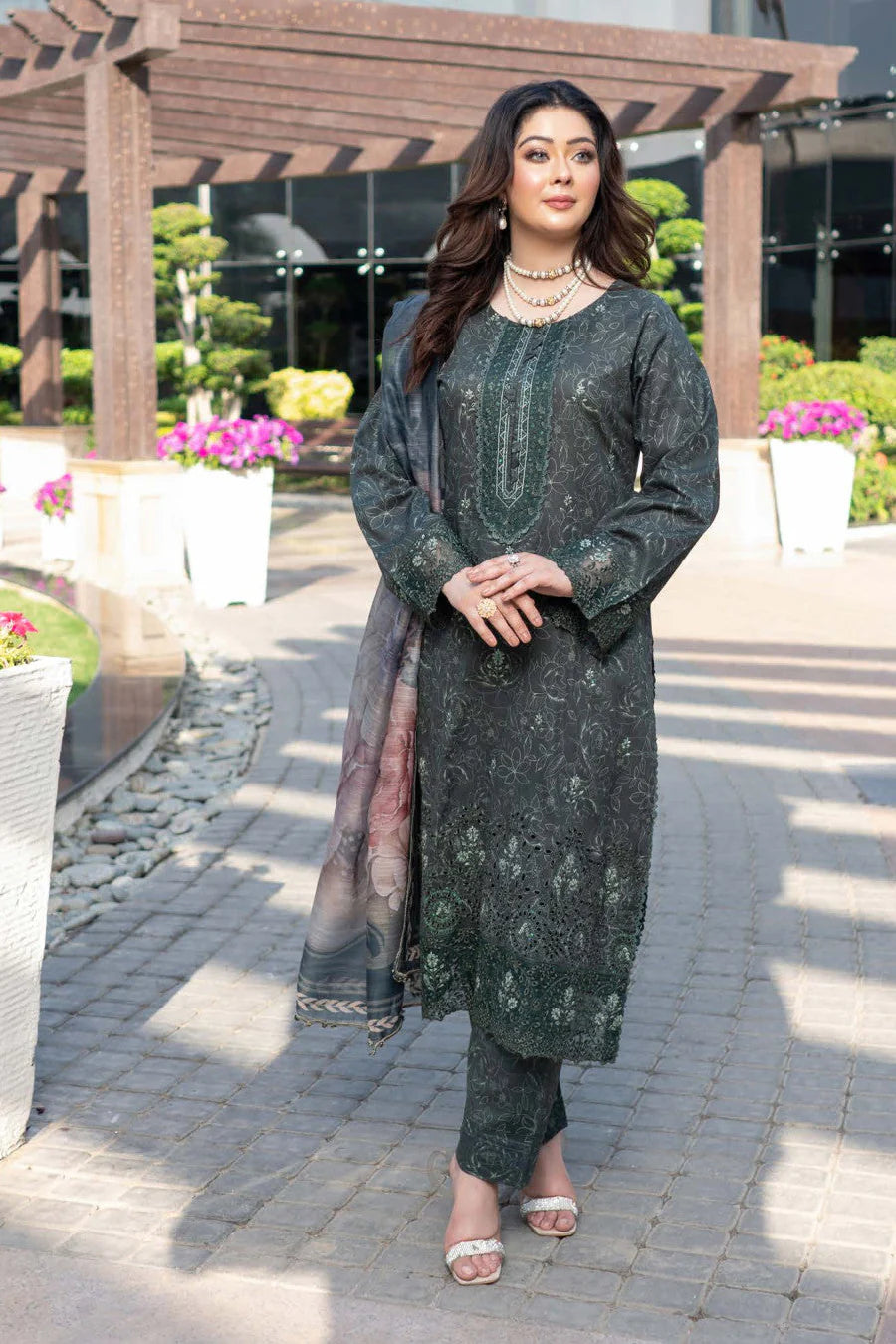 Femme élégante portant des habits pakistanais, shalwar kameez, (ou salwar kameez), habits traditionnels du Pakistan, habits amples, collection printemps été, imprimé en motifs émeraude et noir, avec un shawl léger (écharpe ou foulard) en linon, en imprimé motif émeraude, et un pantalon coupe patte d'éléphant.